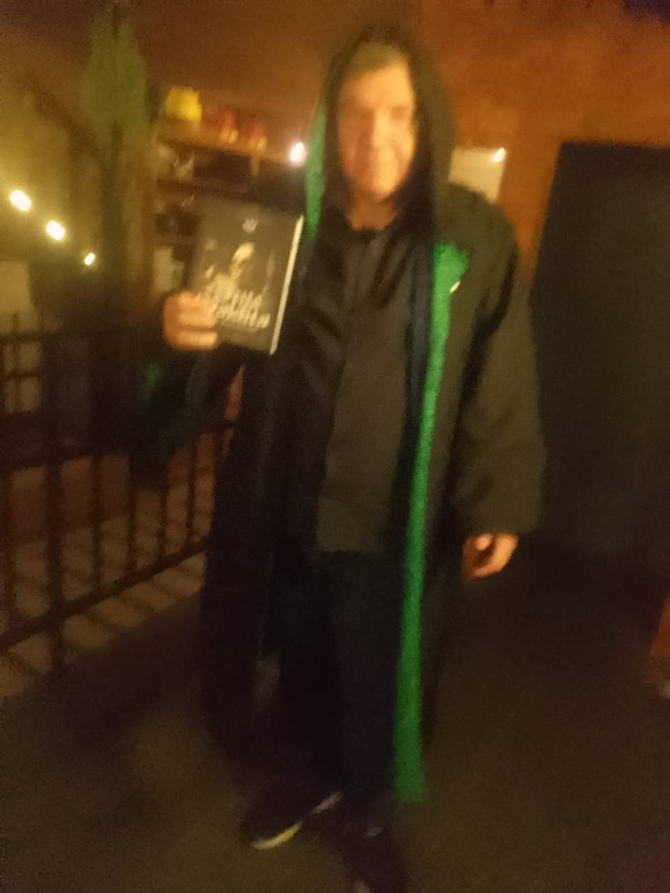 J. Angelini de capuz verde segurando A Seita Maldita no evento de lançamento