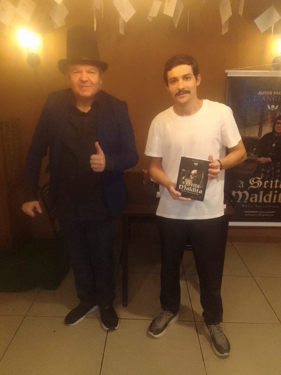 J. Angelini com leitor segurando A Seita Maldita em evento