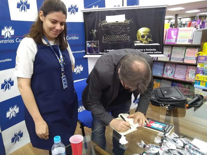 J. Angelini autografando exemplar em livraria