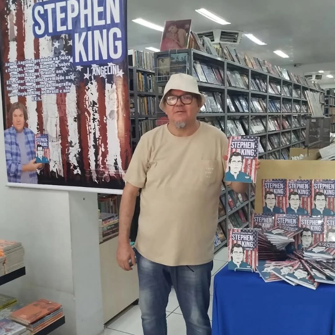 J. Angelini ao lado do banner e dos exemplares em livraria