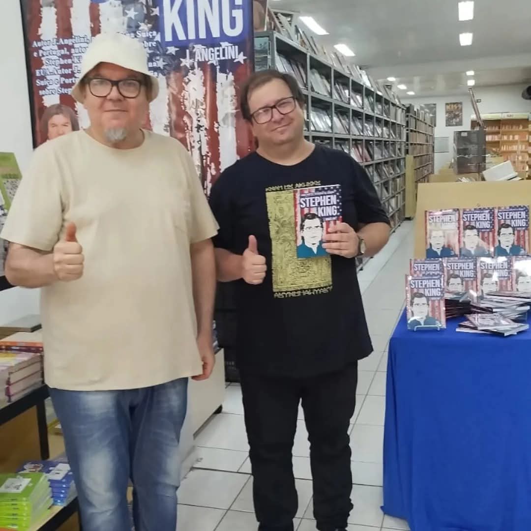 J. Angelini com leitor e pilhas de exemplares em livraria