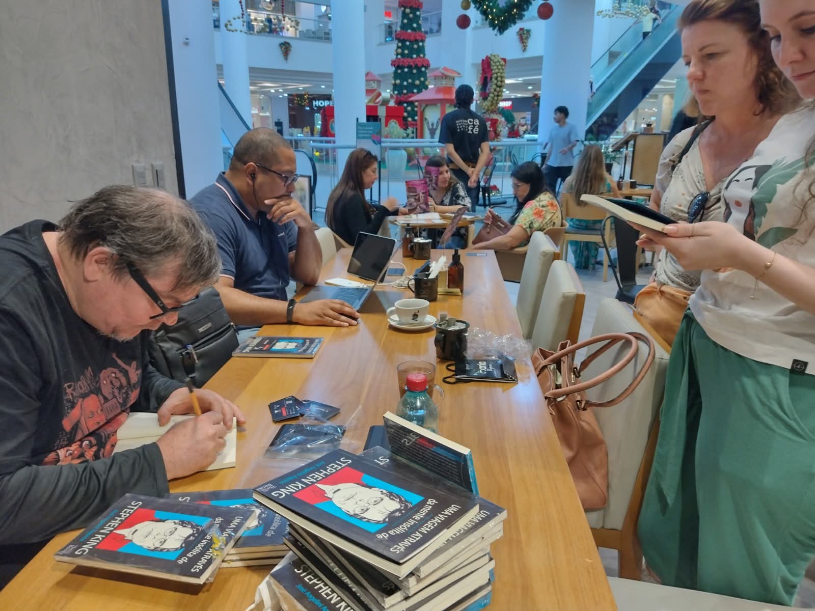 autor em sessão de autógrafos do livro sobre Stephen King em café de shopping