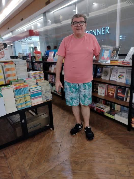 autor ao lado de display com seus livros em evento de lançamento na livraria do shopping